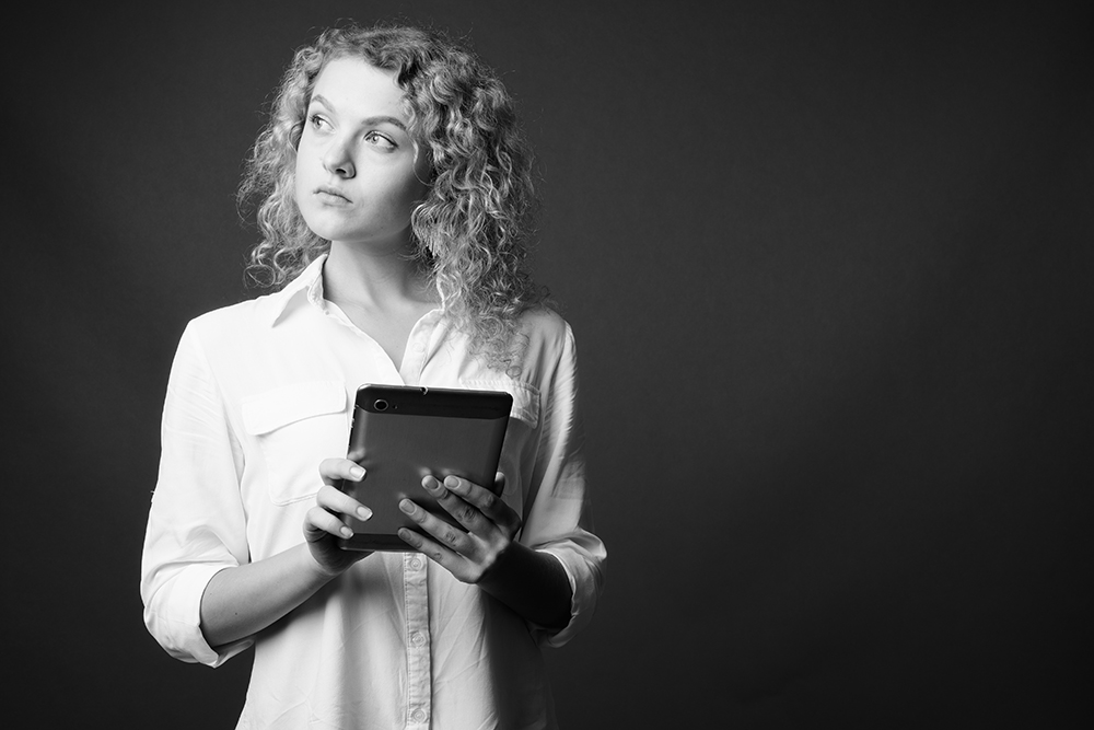 young beautiful businesswoman with curly blond hair against gray background