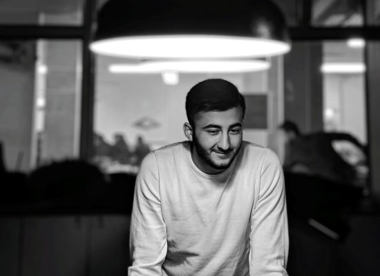 hombre joven sonriendo y mirando hacia otro lado mientras esta de pie debajo de la luz iluminada